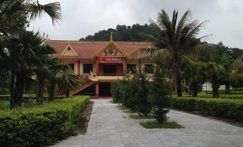 Nhà triển lãm mái đỏ truyền thống nằm giữa cây cọ và vườn cây tại khu di tích Đền Hùng, Phú Thọ.