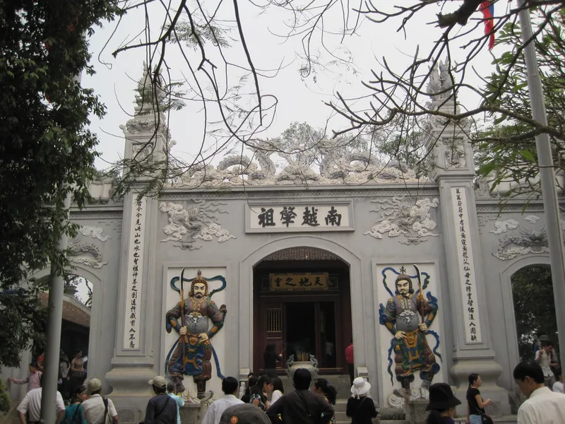 Du khách tụ tập trước cổng đá chạm khắc tinh xảo của đền Thượng, Đền Hùng với tượng thần hộ pháp sơn màu.