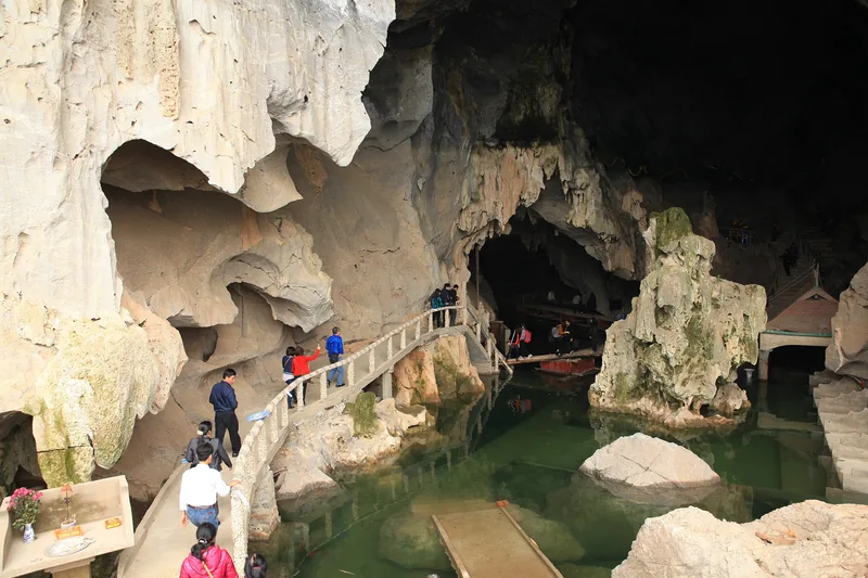 Du khách đi trên cầu gỗ bắc qua hồ nước xanh trong hang đá vôi gần Thung Nai Du khách đi trên cầu gỗ bắc qua hồ nước xanh trong hang đá vôi gần Thung Nai